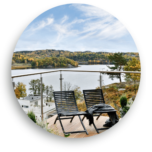 Glass balustrade with stainless steel posts on a timber terrace overlooking a lake. Two sun loungers are placed by the railing, creating an inviting spot to enjoy the view.