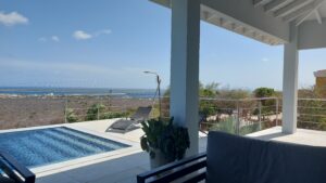 Pool med rækværk i rustfrit stål og horisontale stålwirer, monteret på terrasse med panoramaudsigt over kyst og hav.