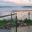 Stainless Steel Glass Balustrade with Rounded Handrail Elegant glass balustrade with rounded stainless steel handrail on timber terrace, facing lake and glowing sunset.
