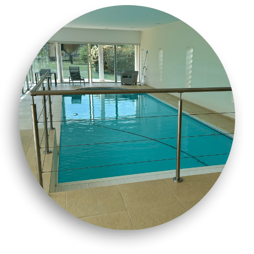 Inomhuspool med stilrent vajerräcke i rostfritt stål och överliggare, ger trygg avgränsning i modern miljö.