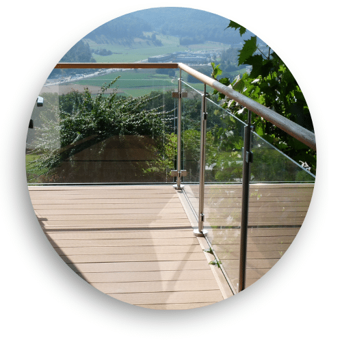 Garde-corps vitré avec main courante en bois installé sur terrasse surélevée avec vue dégagée sur vallée et collines.