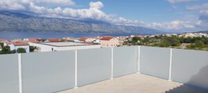 Frosted glass balustrade with mountain sea view Balcony with white frosted glass and aluminium posts, offering views over rooftops, sea and distant mountain peaks.