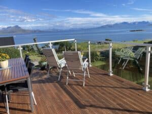 Coastal aluminium balustrade with sea view White aluminium and clear glass deck balustrade facing ocean and mountains, ideal for coastal homes and windy climates.