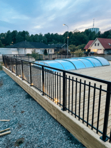 Svart pulverlackerat poolräcke i Alu Retro-design runt altan med trätrall, ger klassisk inramning med hög säkerhet.