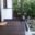 Glass balustrade with gate on timber terrace Frameless glass railing with slim gate on dark timber deck by entryway, black aluminium frame and garden view.
