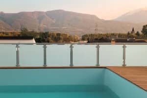 Frosted glass pool fence for privacy and mountain views Frosted safety glass railing by terrace pool with scenic mountain backdrop and warm sunset lighting, offering wind and privacy protection.