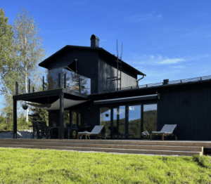 Moderni lasikaide mustilla tolpilla ja savulasilla yläterassilla, asennettu mustaa puujulkisivua vasten