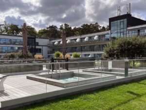 Glass safety railing by hotel pool in urban setting Elegant laminated glass railing with round posts around city hotel pool, combining modern safety with a sleek, professional finish.