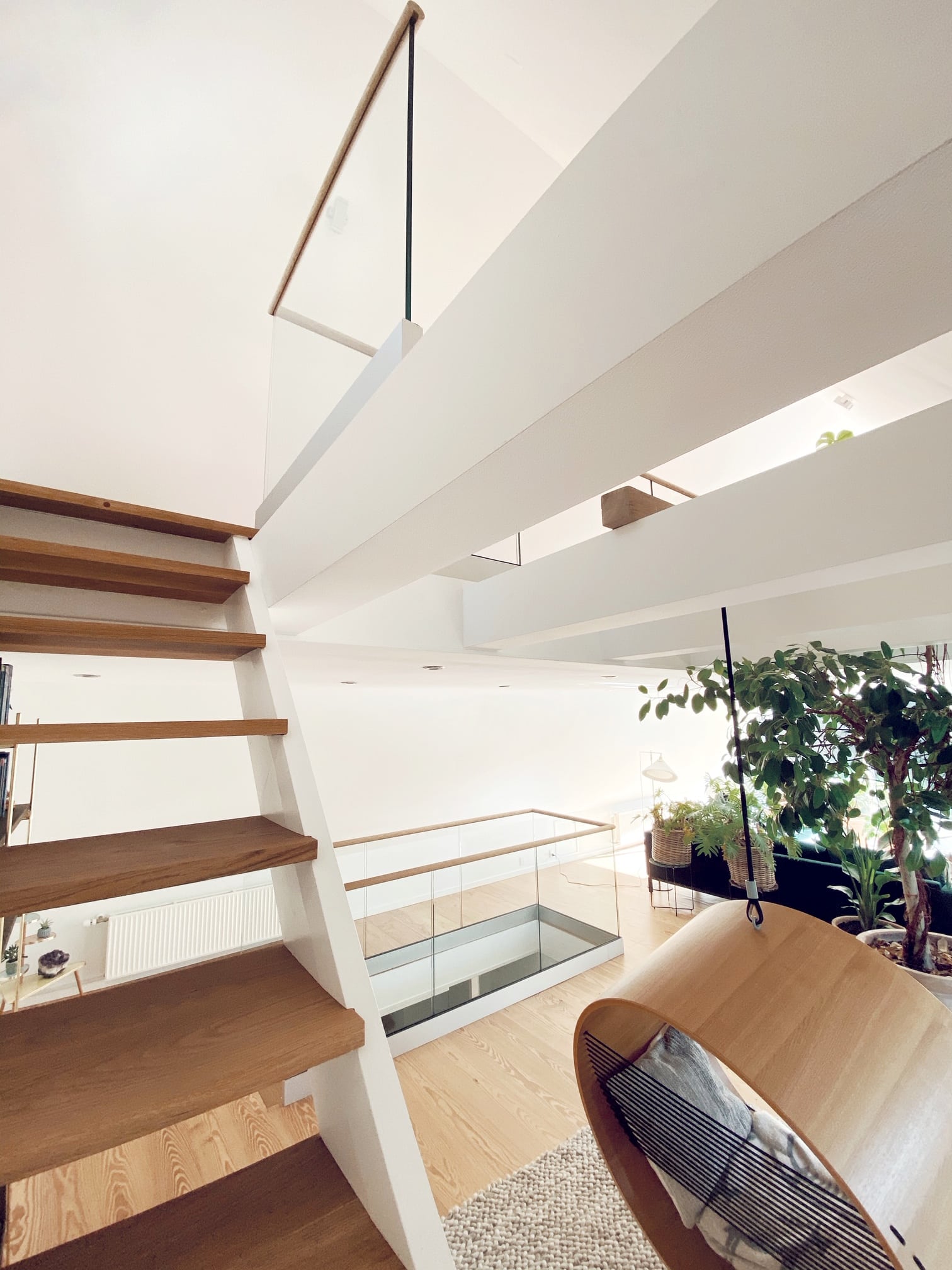 Indendørs hems med glasgelænder uden stolper og træhåndlister, omkranser trappe og hems i lyst hjem.