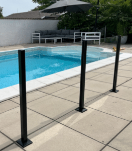 Black-framed glass pool fence on stone patio Modern glass railing with black posts mounted on white tiles around villa pool – stylish, low-maintenance, and CE-certified safe.
