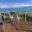 Weißes Geländer mit Bergblick Weißes Glasgeländer mit Klarglas rund um Holzterrasse mit Essbereich und Sesseln mit Blick auf Berge und Meer.