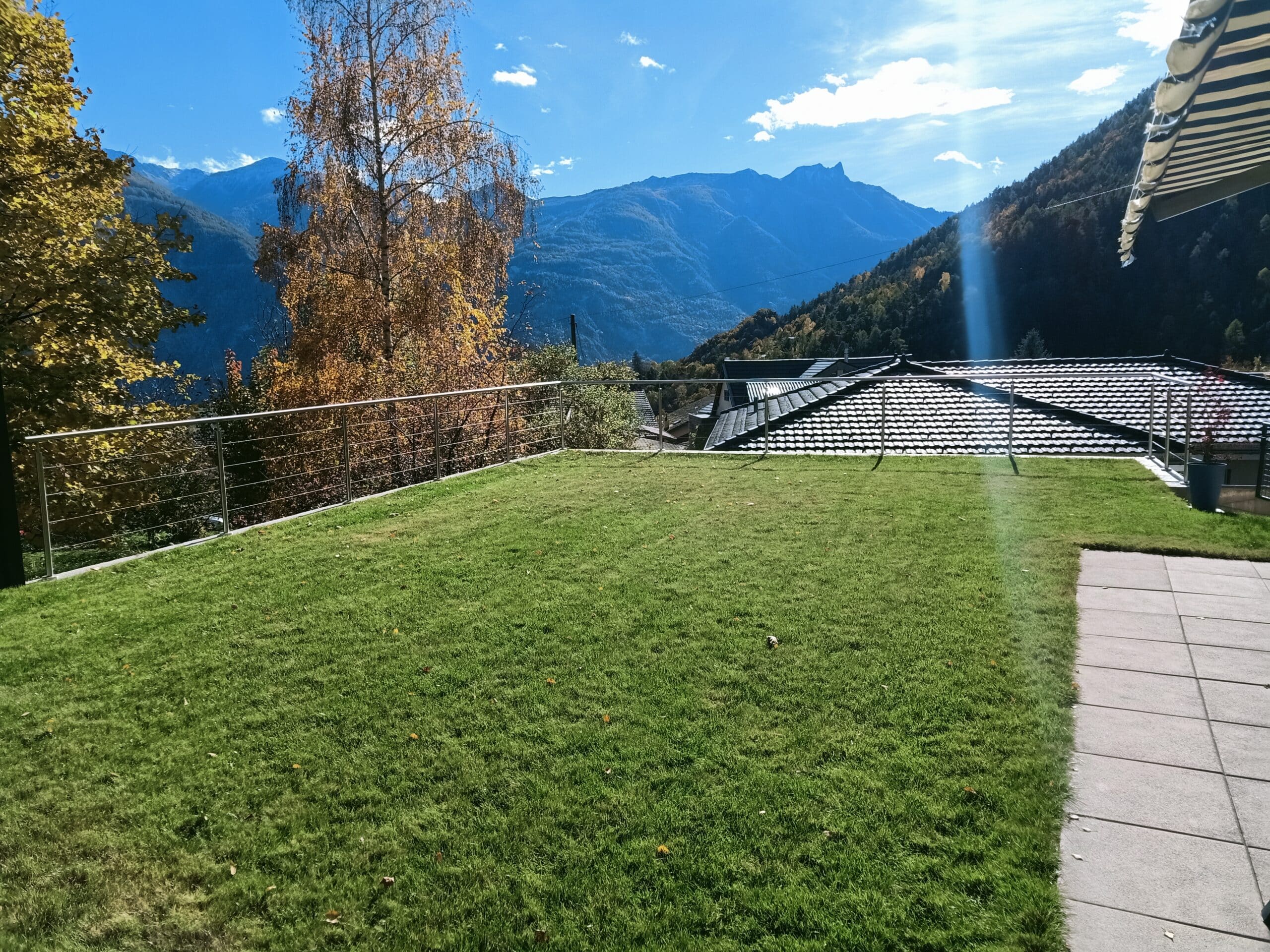Balustrade basse en câble inox entourant toit-terrasse végétalisé avec vue arbres d’automne et montagnes enneigées.