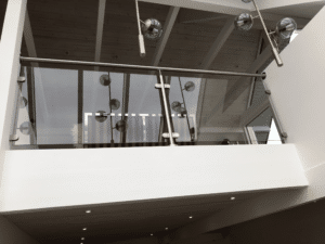 Glasgeländer mit Edelstahlhandlauf Loft mit Rauchglas-Geländer und Edelstahlhandlauf. Minimalistische Halterungen und moderne Beleuchtung spiegeln sich im Glas und unterstreichen das elegante Design.