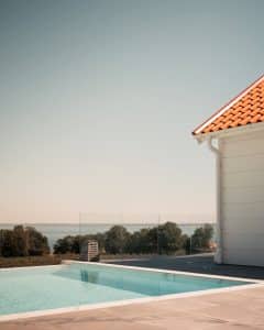 Pfostenfreies Glasgeländer am Pool mit Meerblick Elegantes pfostenfreies Glasgeländer aus Klarglas am Pool, mit Blick auf das Meer und Baumkronen – offen und luxuriös.