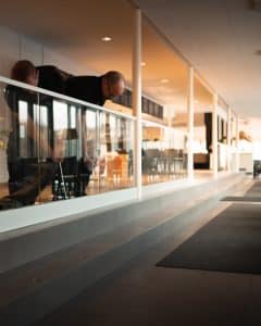 Fachgerechte Montage in moderner Umgebung Zwei Monteure installieren ein stilvolles pfostenfreies Glasgeländer in einem hellen, modernen Raum mit offener Einrichtung.